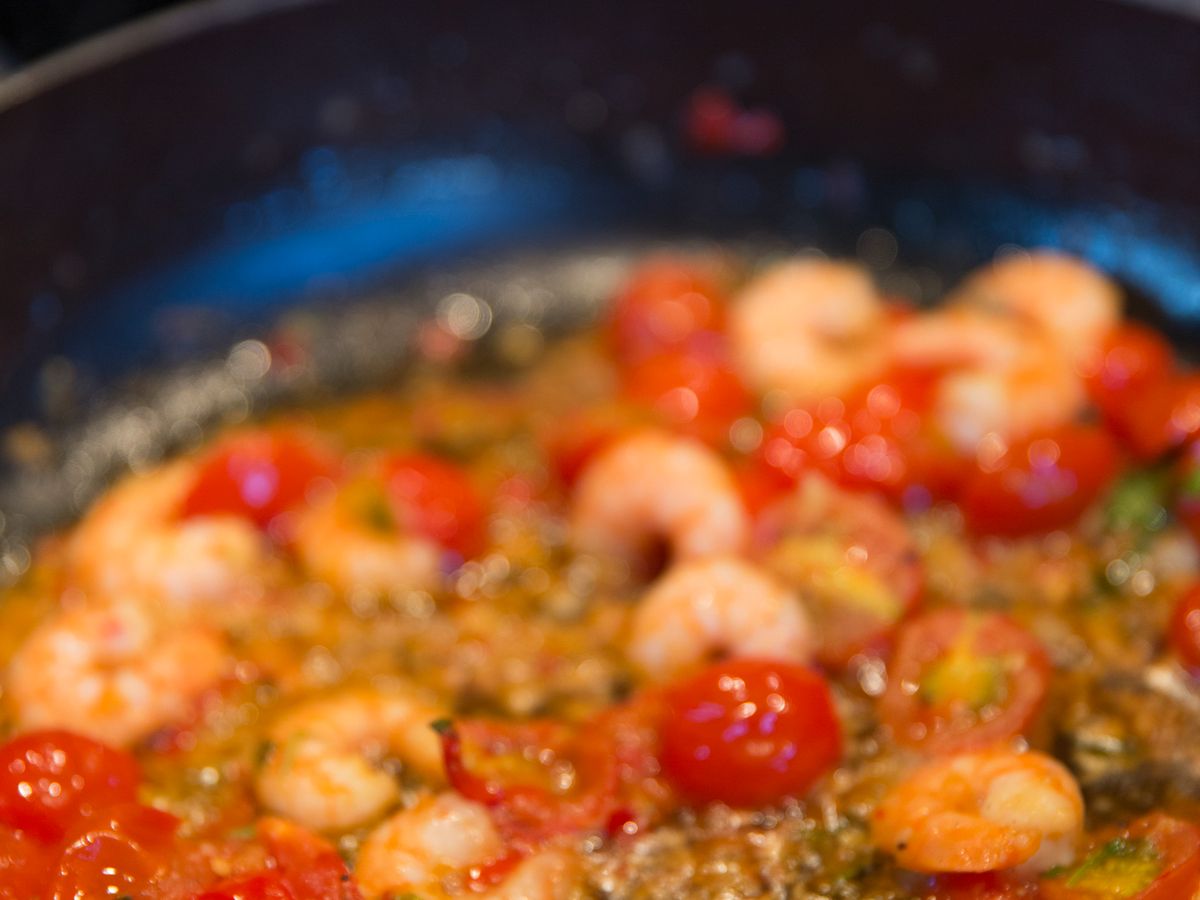 Garlic butter shrimp and cherry tomatoes cooking in a skillet, one of these easy dinners for one