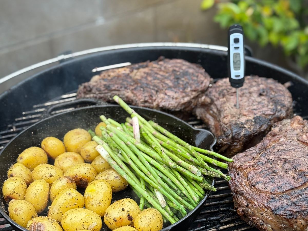 Digital food thermometer inserted into a steak on a grill, checking safe temperature for one of these easy dinners for one