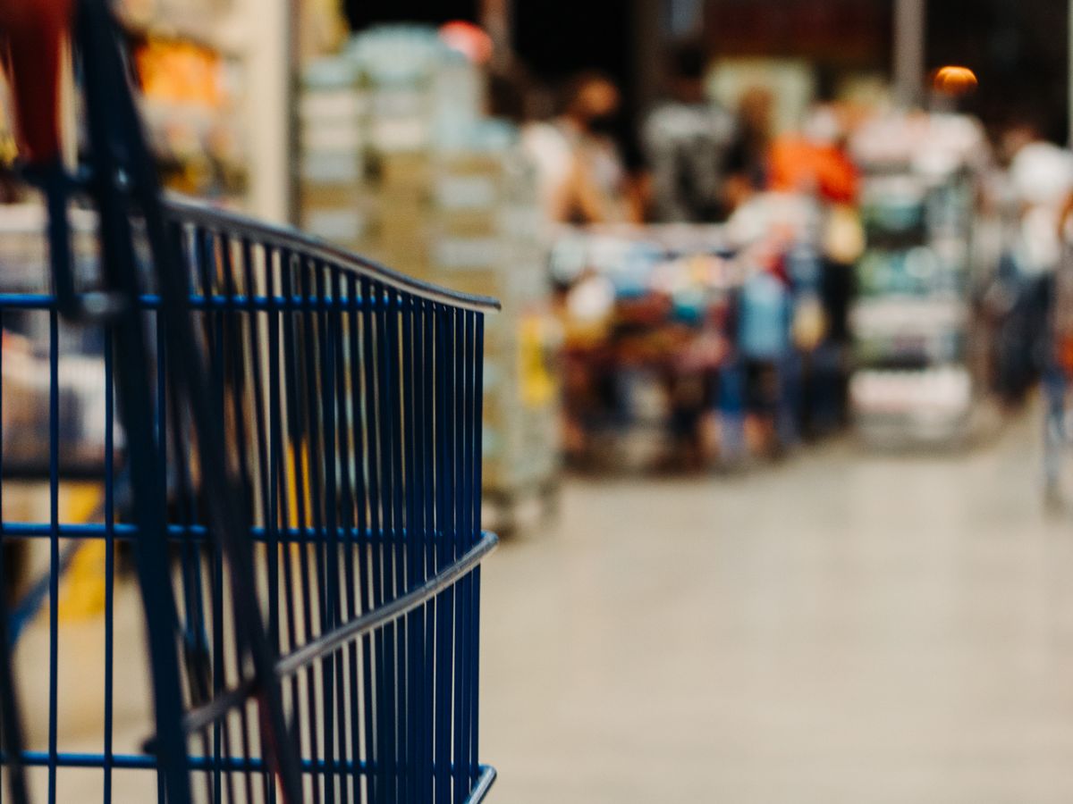 Shopping cart moving down a grocery store aisle, illustrating how to compare unit prices while shopping for one