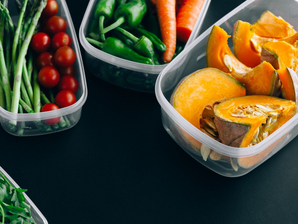 Three plastic containers of fresh vegetables and pumpkin stored for meal prep in the refrigerator