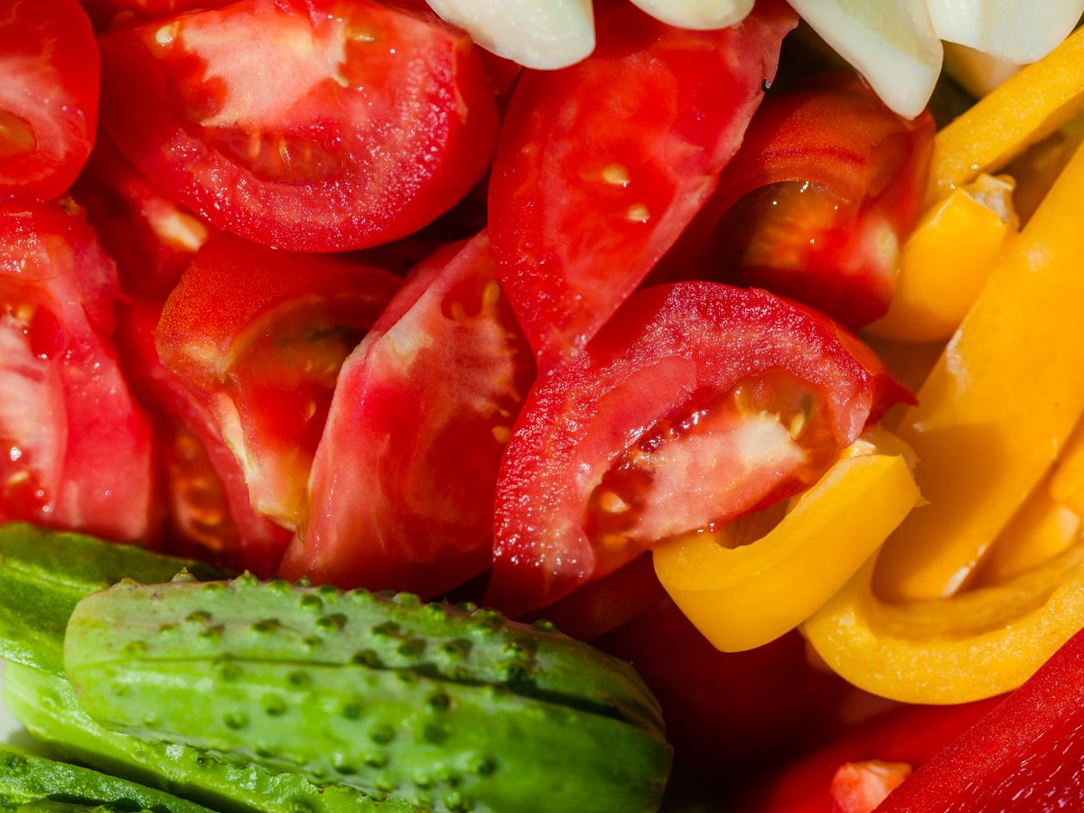 Close-up of fresh vegetables including tomatoes, peppers, and cucumber for a single-person grocery haul