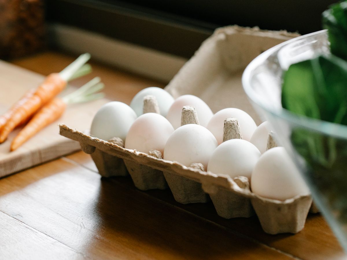 Carton of eggs and fresh carrots on a kitchen counter, used as anchor ingredients when you plan a week of meals for one